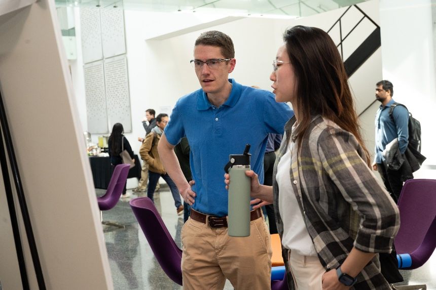 Mathematics students and faculty looking at research poster