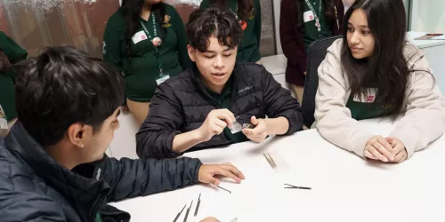 Three high-school students sitting at a table picking locks