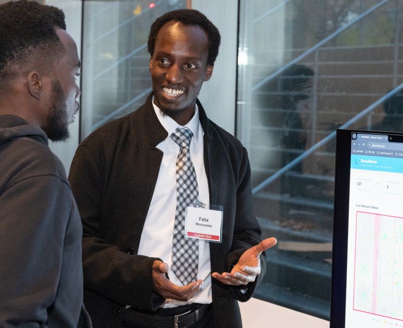 Student researcher explains his data science project to a fellow student